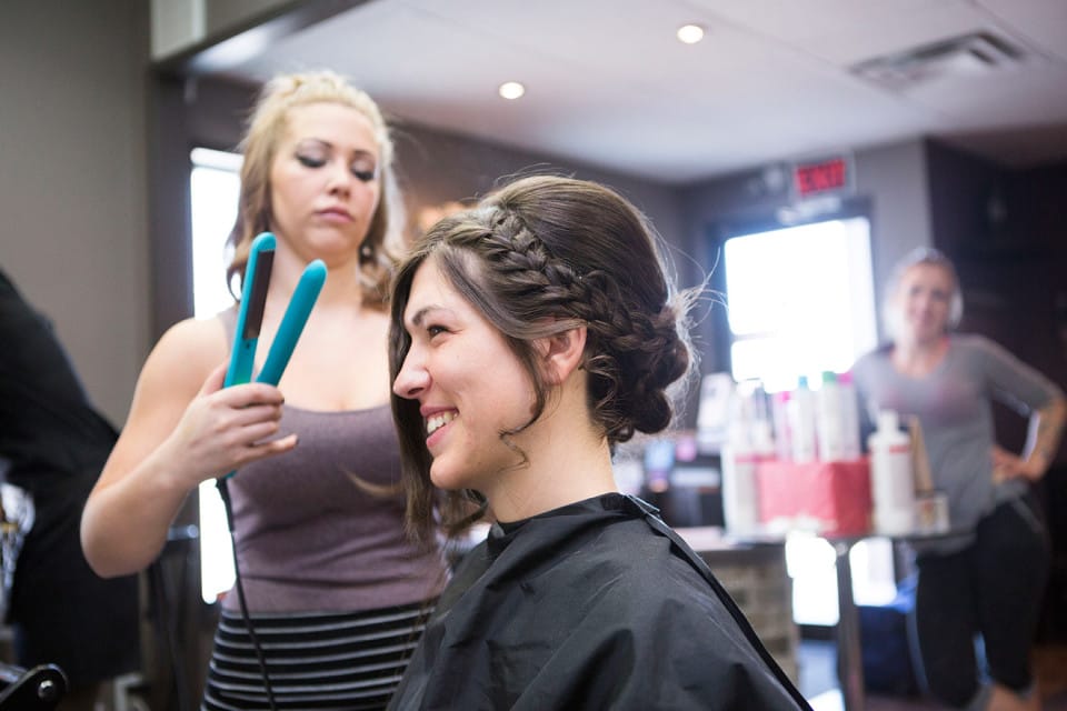 A bride smile while having their hair done during wedding day preparations in Prince Albert