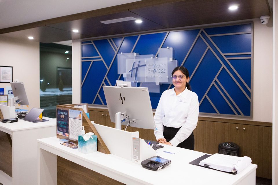 A receptionist stands next to computer at the holiday inn in Prince Albert, example of commercial photography by UBU Photos