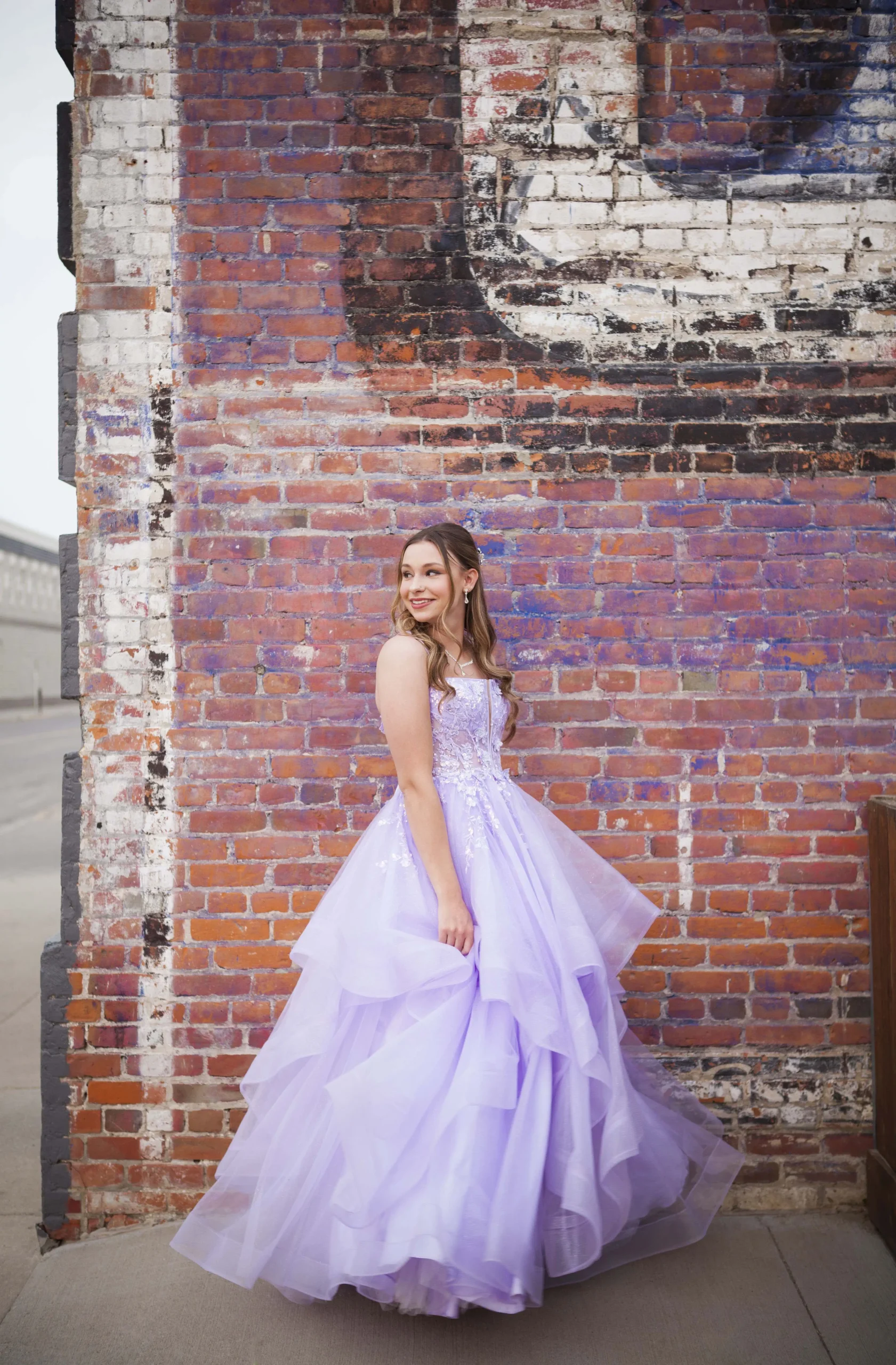 Prince Albert graduation photographer, example of photography by UBU Photos of a grad standing in dress next to downtown brick buildings